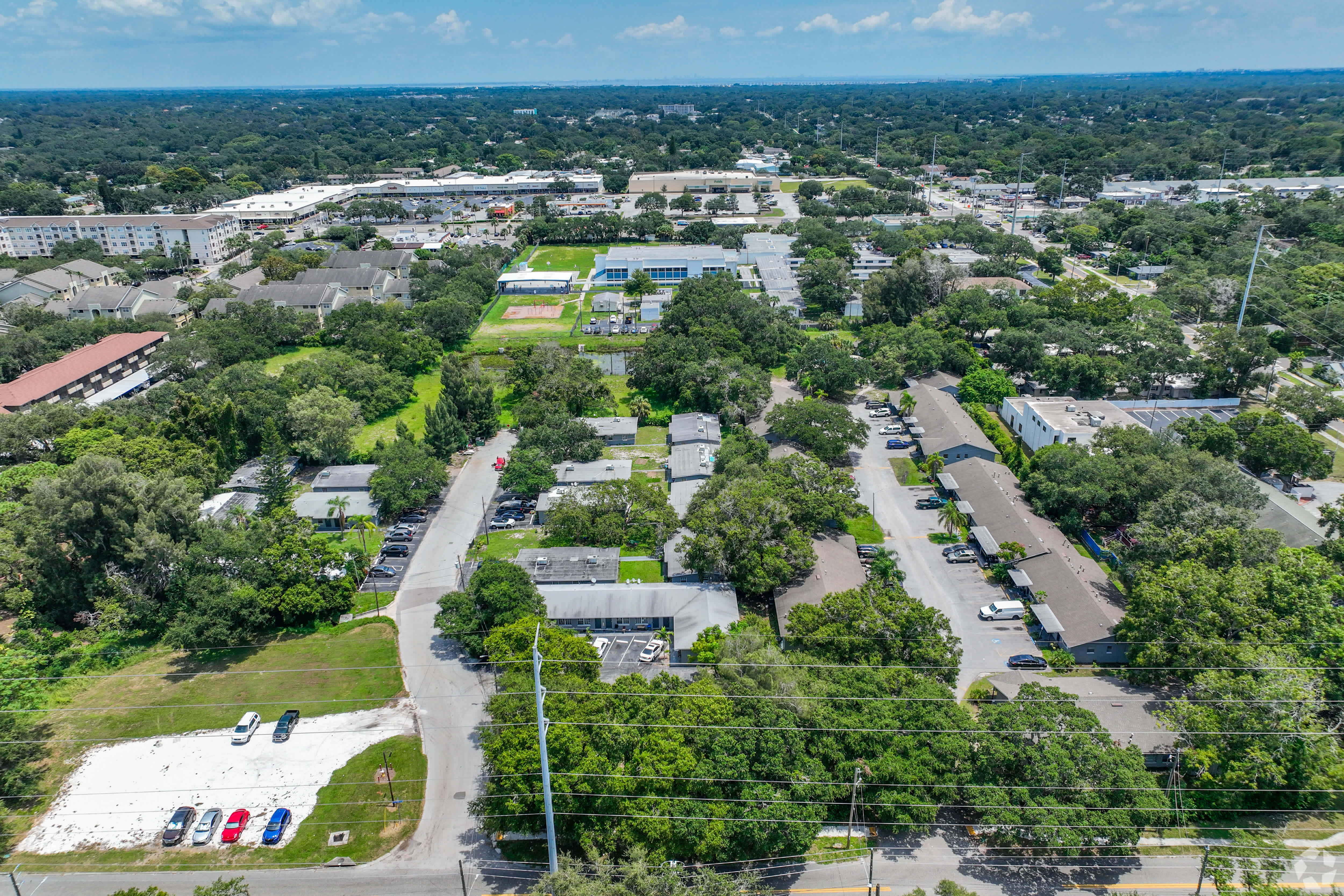 Aerial view of The Oasis at Clearwater — eight low-slung buildings under a canopy of mature oaks
