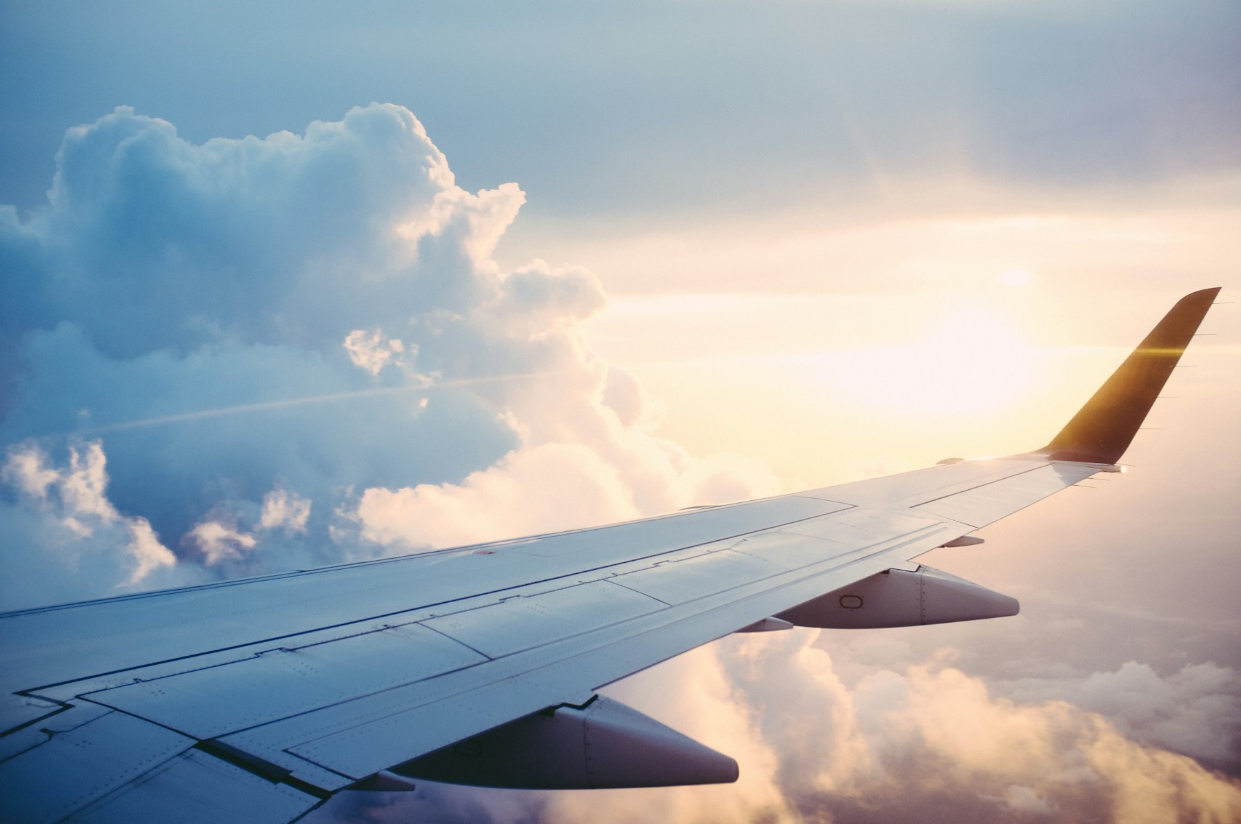 An airplane wing above the clouds at sunset